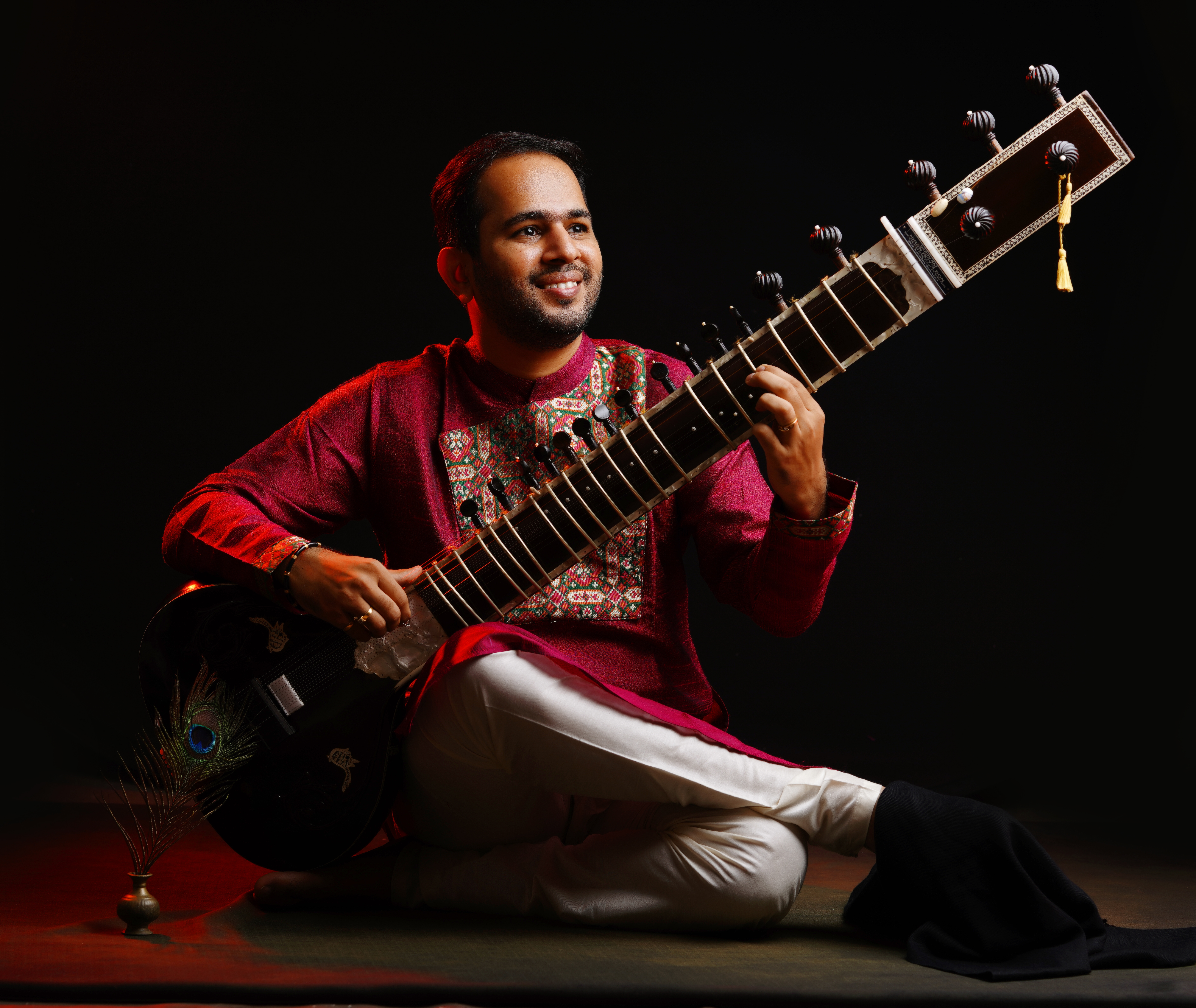 Ankush N Nayak in maroon attire holding the sitar
